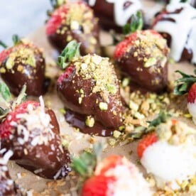 how to make chocolate covered strawberries - chocolate covered strawberries on parchment paper on a marble surface