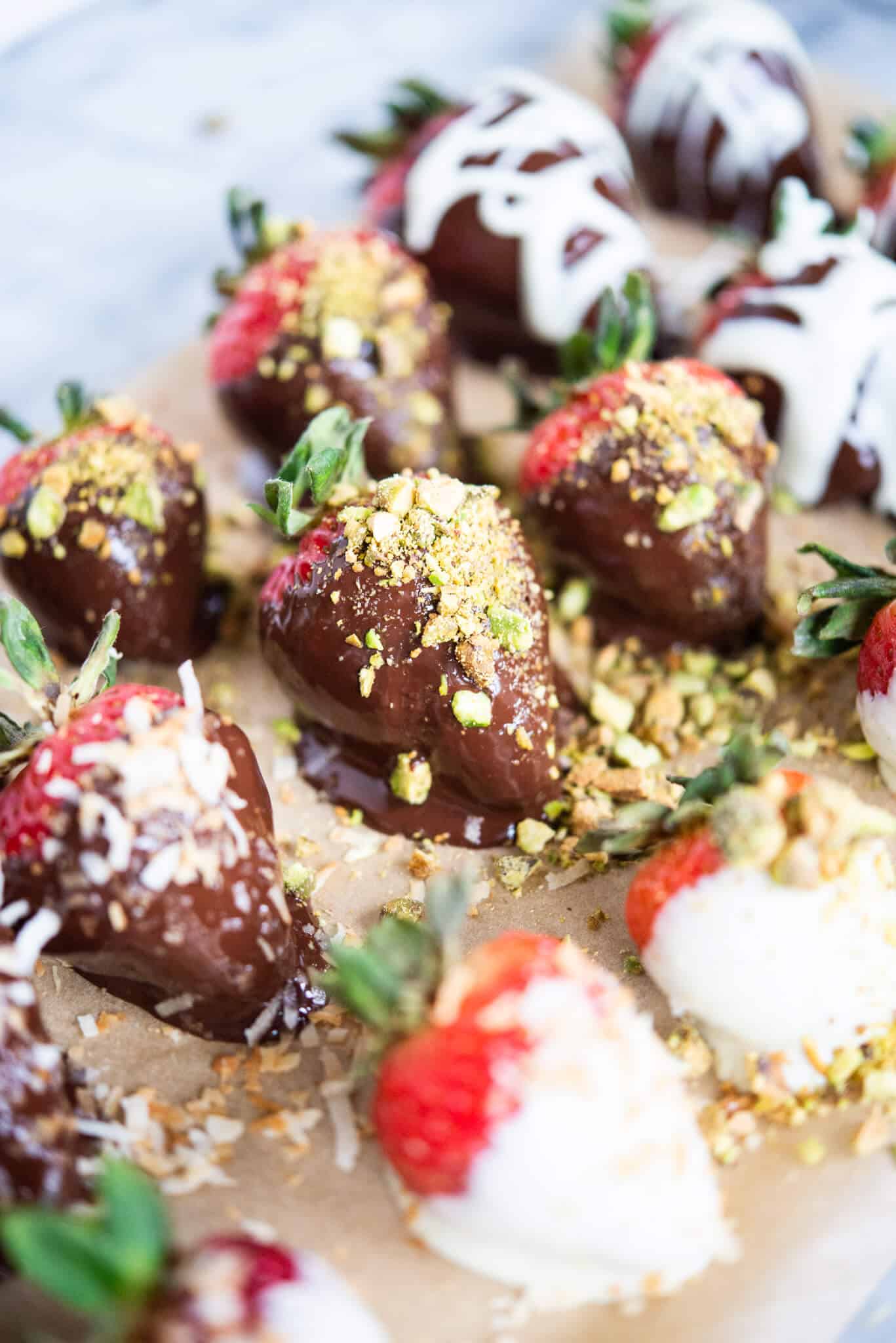 how to make chocolate covered strawberries - chocolate covered strawberries on parchment paper on a marble surface
