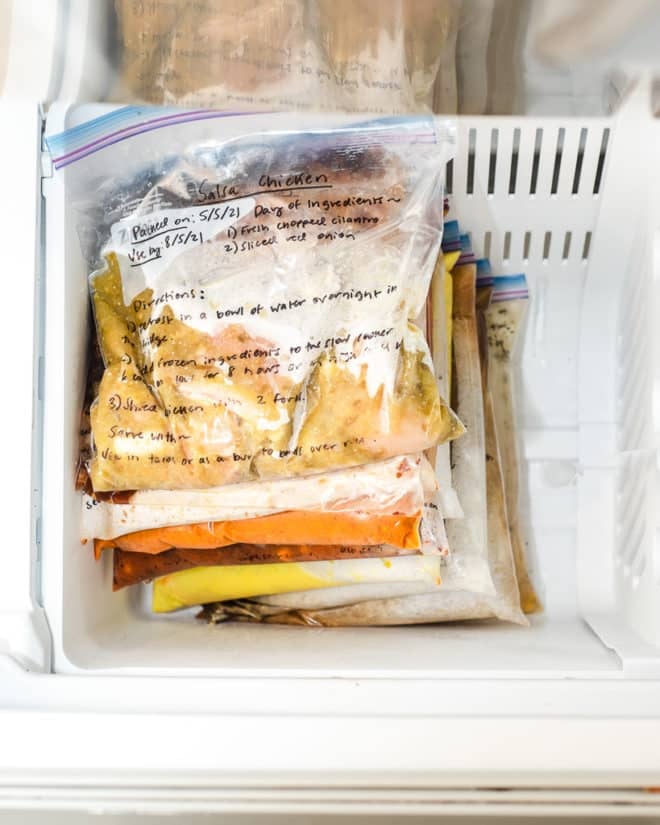 Ziplock bags with writing on them filled with food and stacked in the freezer