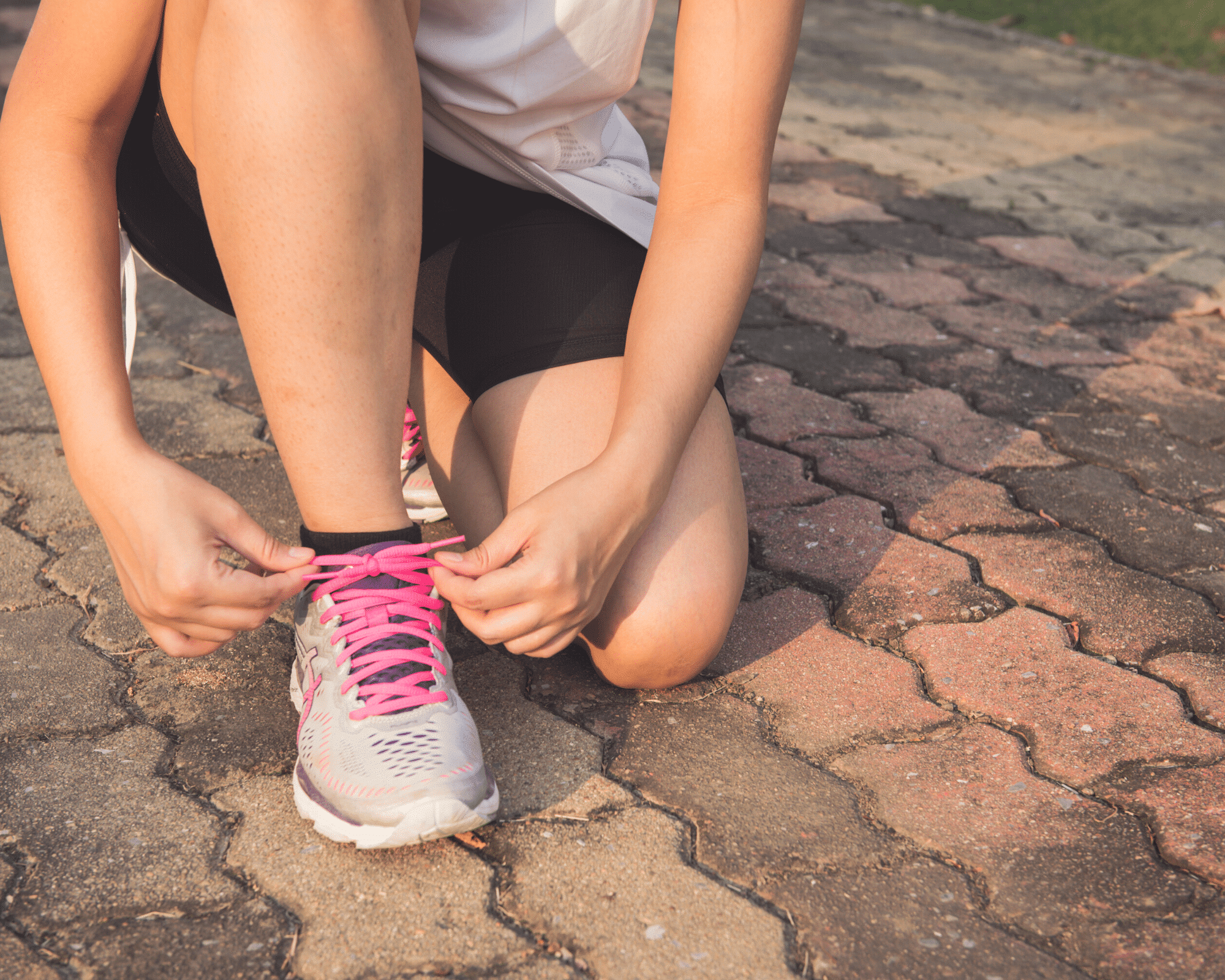 woman tying her sneakers with bright pink laces