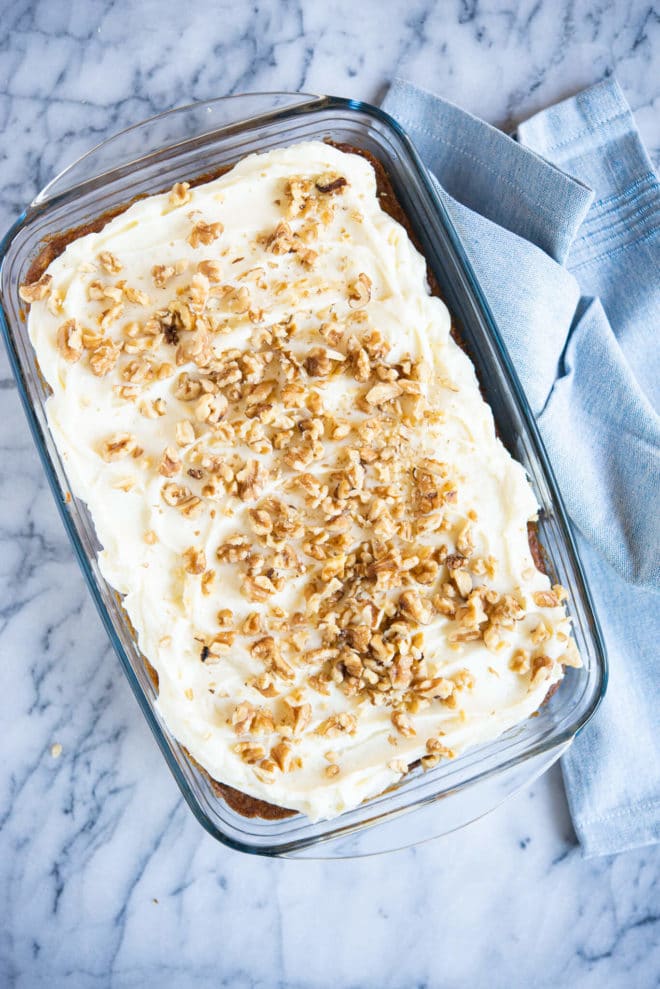 gluten free carrot cake before being cut into pieces in a clear baking dish on a marble surface