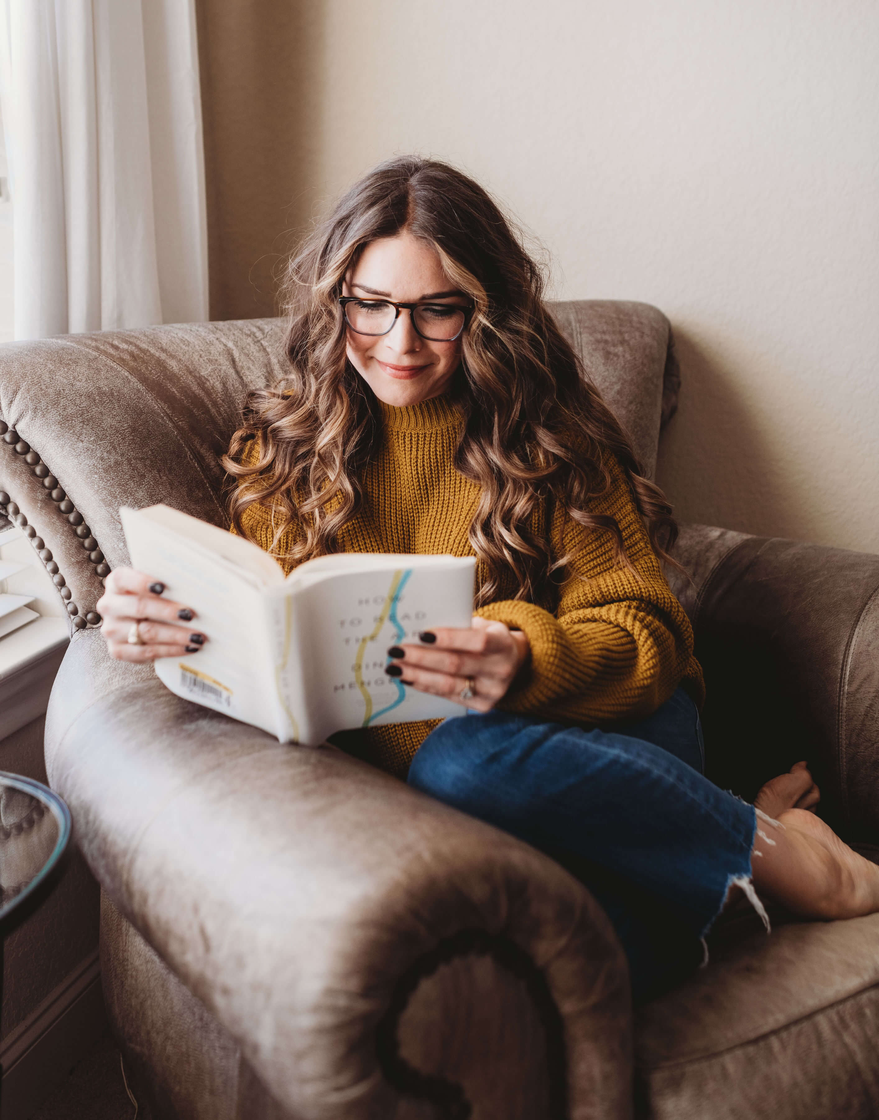 woman in a brown leather chair reading a book