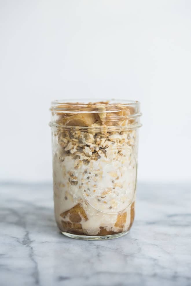 apple cinnamon overnight oats in a glass mason jar on a marble surface