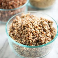 perfectly cooked tri-color quinoa in a circular glass bowl on a marble surface