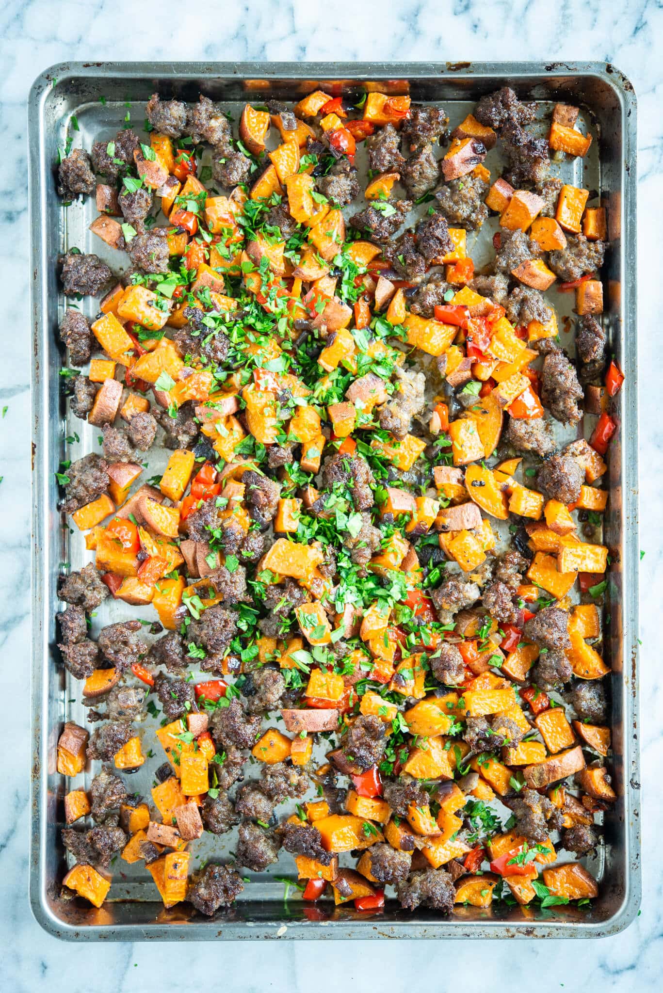 sweet potato hash - crumbled sausage, bell pepper, and sweet potato breakfast hash on a sheet pan on a marble surface