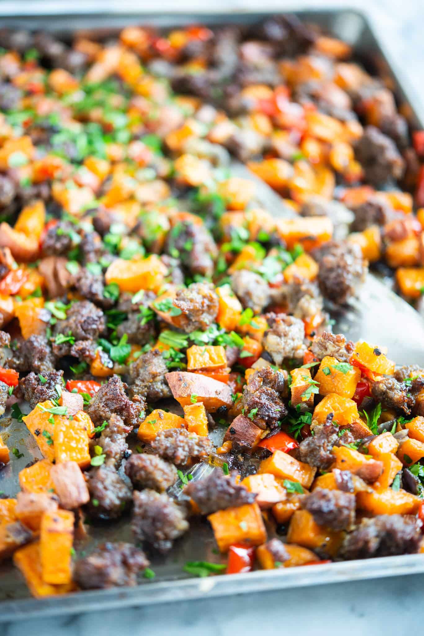 sweet potato hash on a sheet pan - crumbled sausage, bell pepper, and sweet potato breakfast hash on a sheet pan on a marble surface