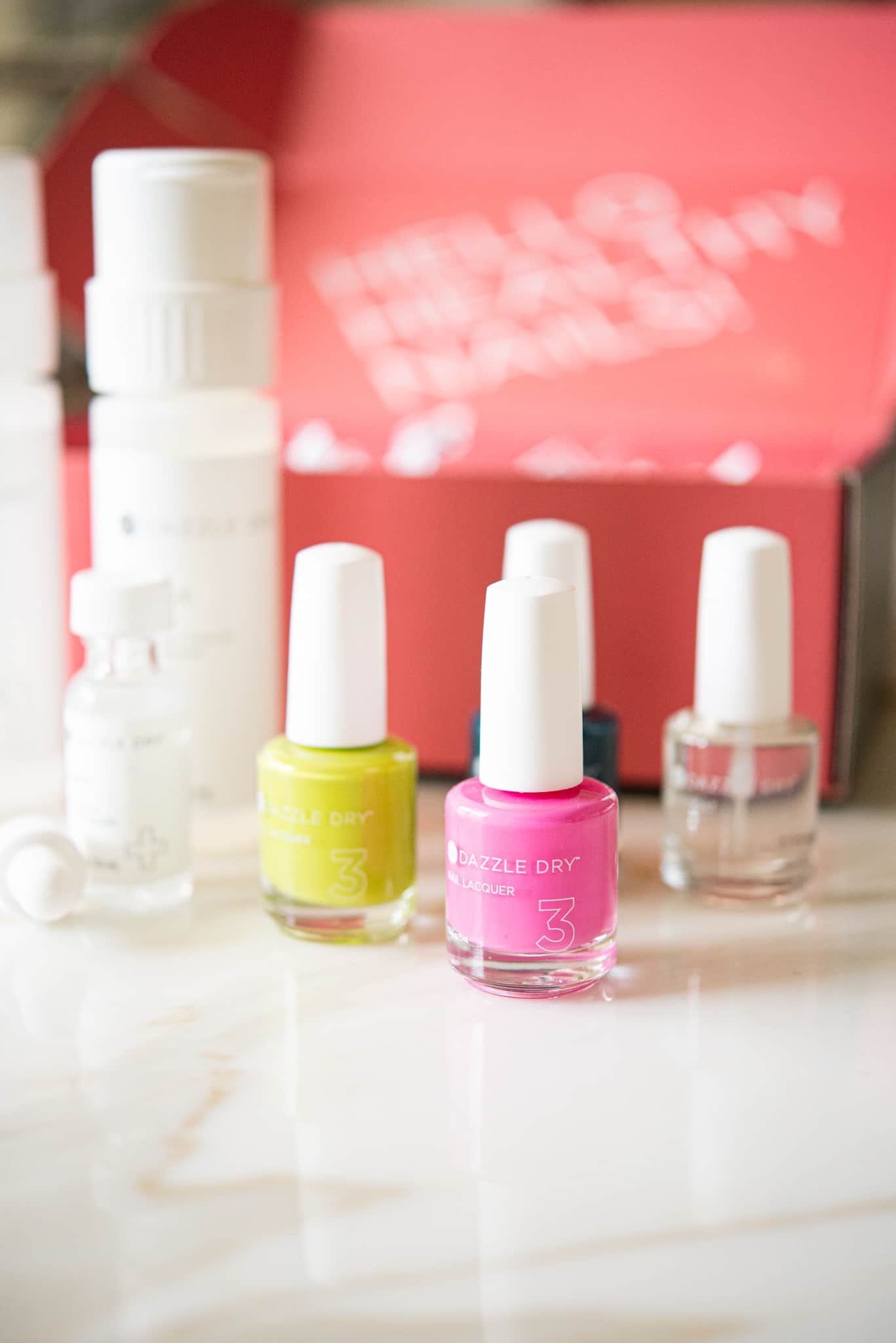 pink nail polish with yellow and clear polish behind it in front of a pink box - dazzle dry nail system