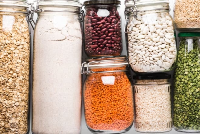 Variety of grains and legumes in glass jars, top view