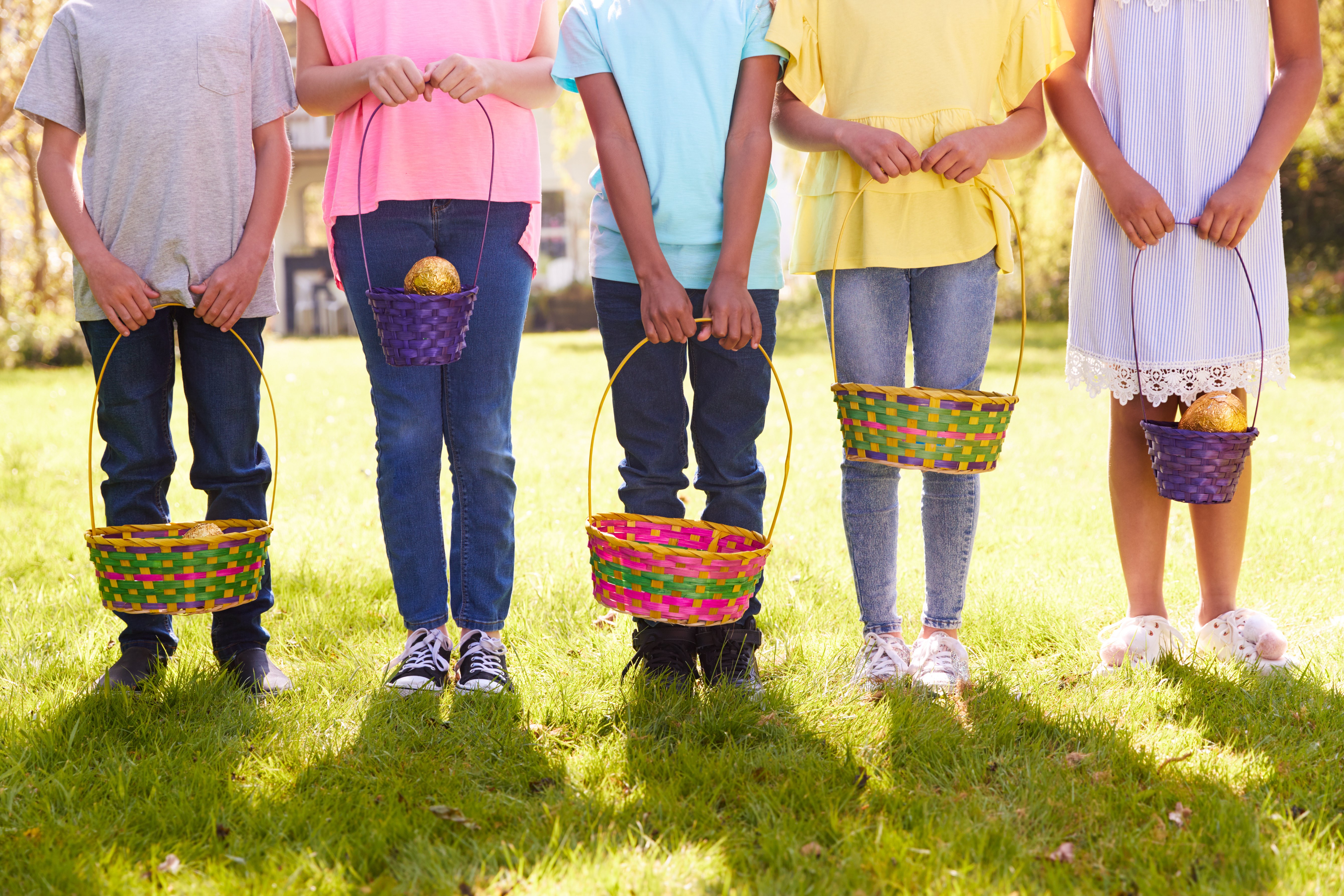 Close Up Of Five Children Holding Baskets On Easter Egg Hunt In Garden