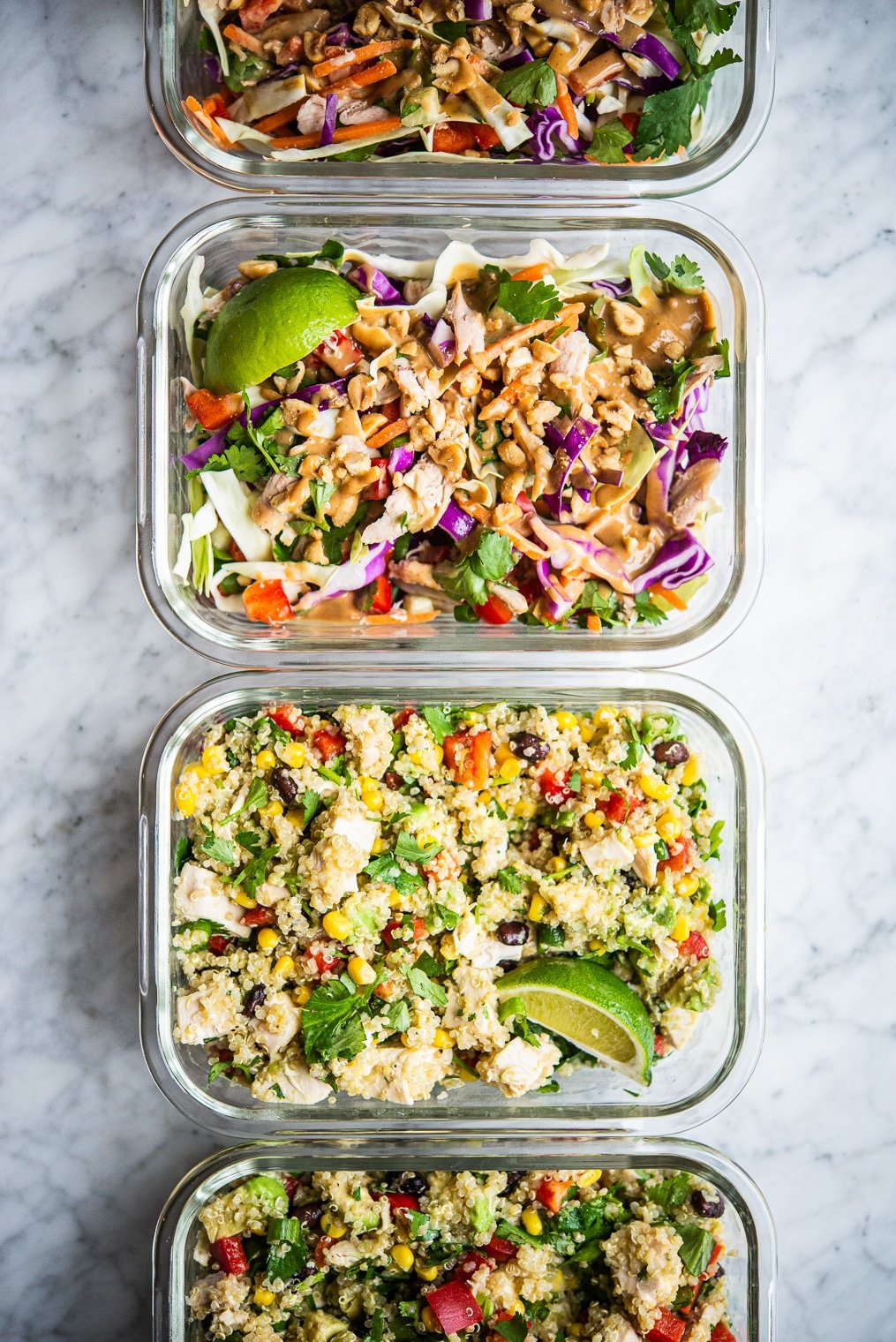 thai chicken salad and southwestern quinoa salad in clear individual portion containers on a marble surface