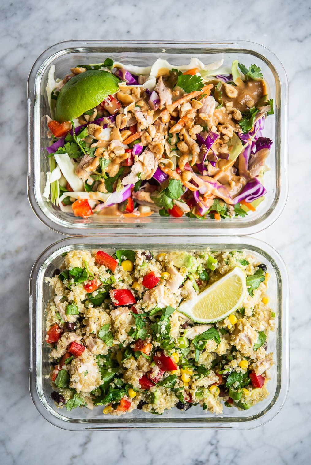 thai chicken salad and southwestern quinoa salad in clear individual portion containers on a marble surface