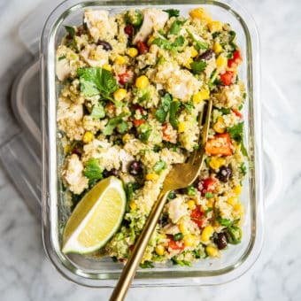 southwestern quinoa salad garnished with a lime wedge and cilantro in a glass bowl on a marble surface