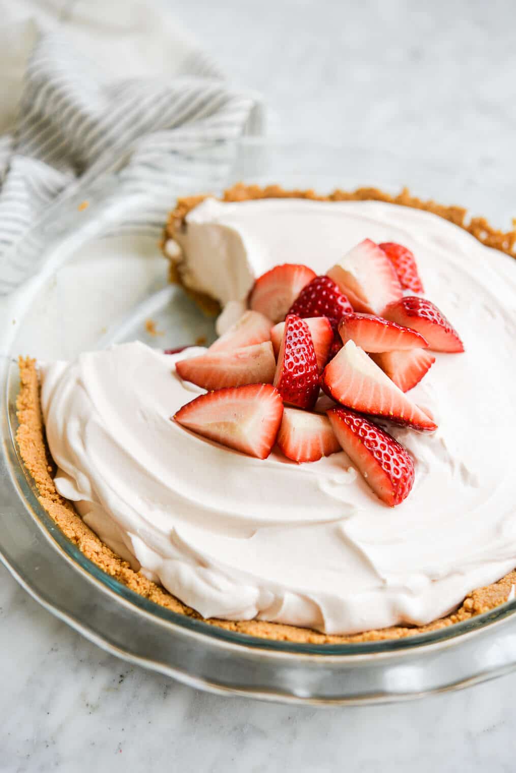 strawberry yogurt pie in a graham cracker crust with chopped strawberries on top