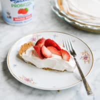 slice of strawberry yogurt pie on a floral china patterned plate with a fork sitting on a marble surface