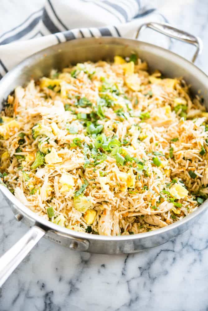 chicken and broccoli fried rice in a stainless steel pan on a marble surface