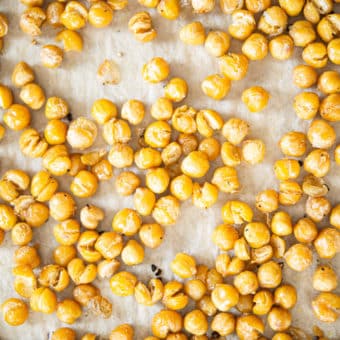 crispy roasted chickpeas on a parchment paper lined baking sheet on a marble surface