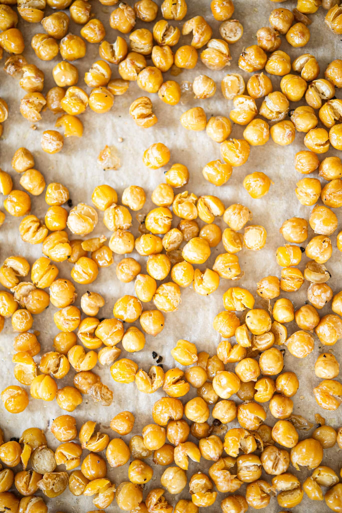 crispy roasted chickpeas on a parchment paper lined baking sheet on a marble surface