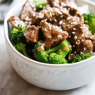 instant pot beef and broccoli over white rice topped with sesame seeds in a grey bowl on a marble surface