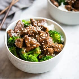 instant pot beef and broccoli over white rice in a white bowl on a marble surface