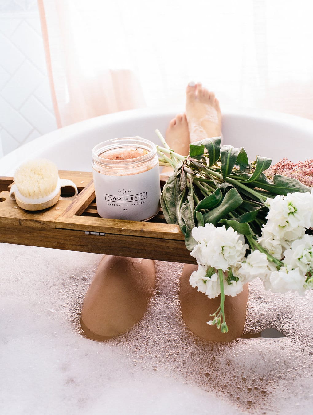 spa day at home - bubble bath with a wooden tub stand with flowers and bath soak