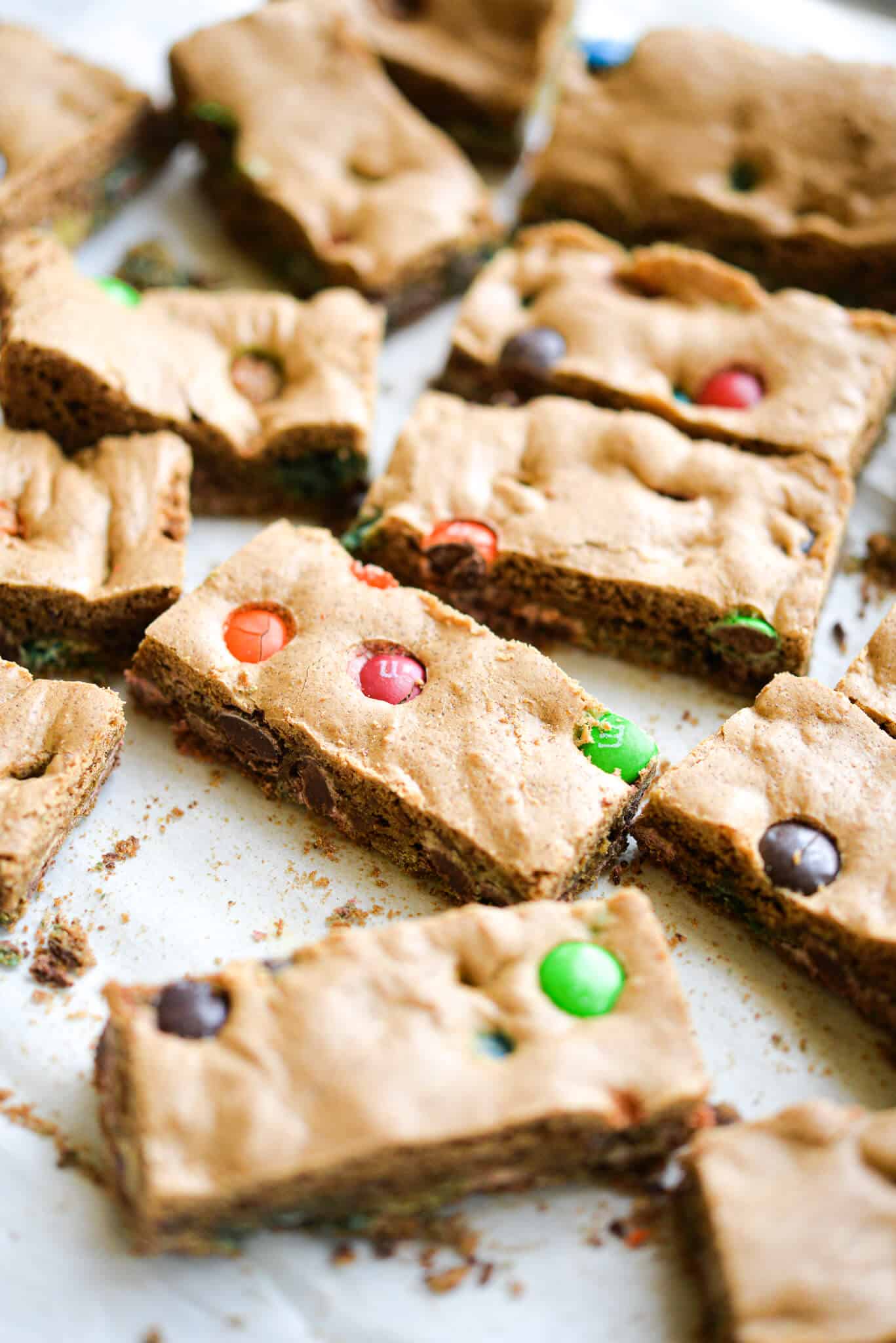 already cut m&m cookie bars spread out on parchment paper