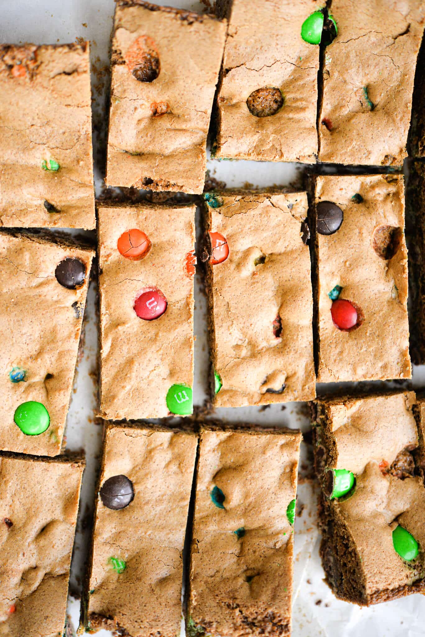 already cut m&m cookie bars spread out on parchment paper