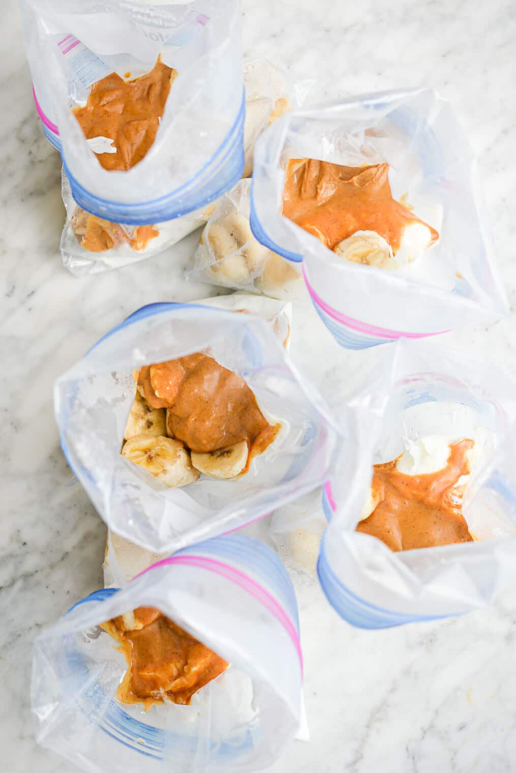 5 open peanut butter banana smoothie packs laying on a marble surface