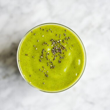 top view of a tropical green smoothie topped with chia seeds on a marble surface