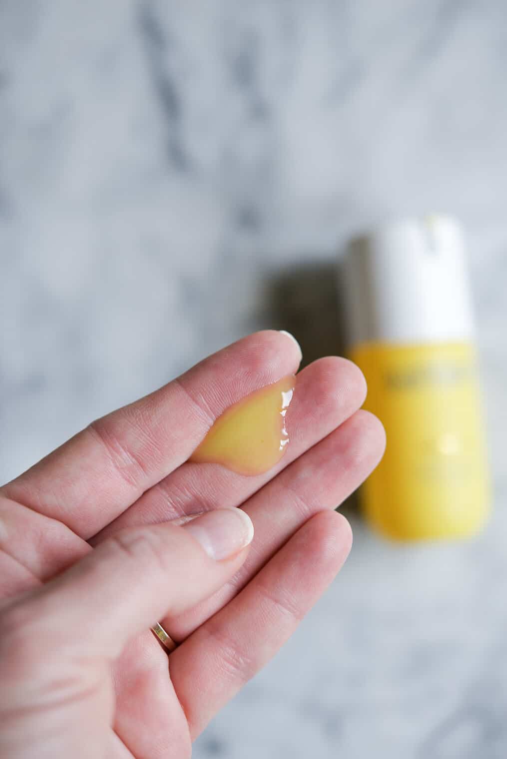 woman's hand with a blob of yellow vitamin c serum on it