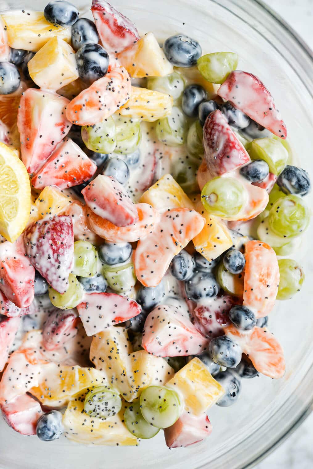 ready to eat yogurt fruit salad in a large glass bowl on a marble surface