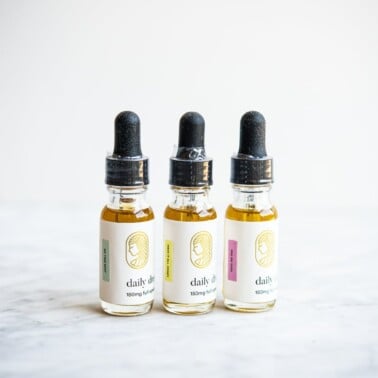 3 bottles of cbd oil lined up in a row on a marble surface