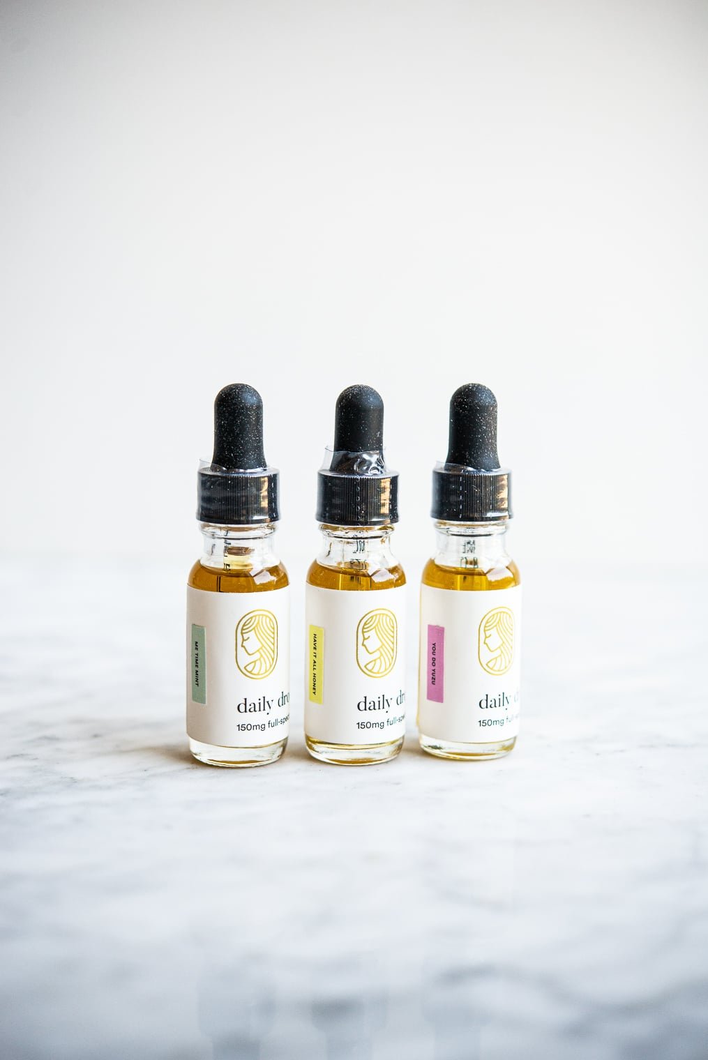 3 bottles of cbd oil lined up in a row on a marble surface