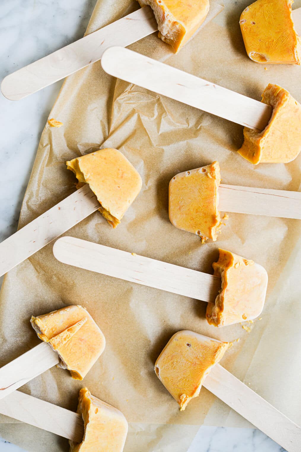 9 finished probiotic yogurt pupsicles laying on parchment paper on a marble surface