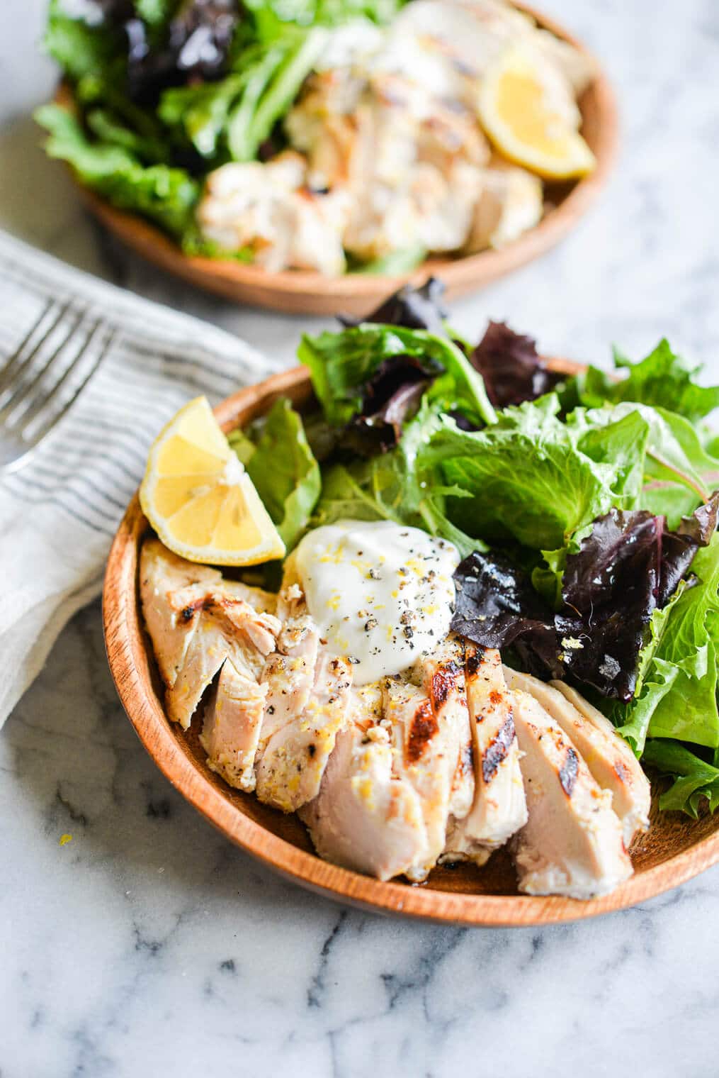 lemon pepper yogurt grilled chicken sliced and served in a bowl on top of mixed greens