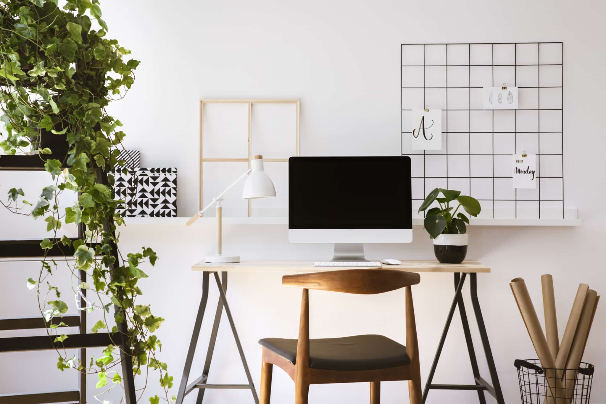 office with a white desk, mac monitor, wooden chair, and a shelf with a plant on it