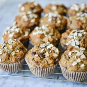 side angle view of chocolate chip banana oat muffins on a wire rack on a marble surface