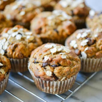 side angle view of chocolate chip banana oat muffins on a wire rack on a marble surface