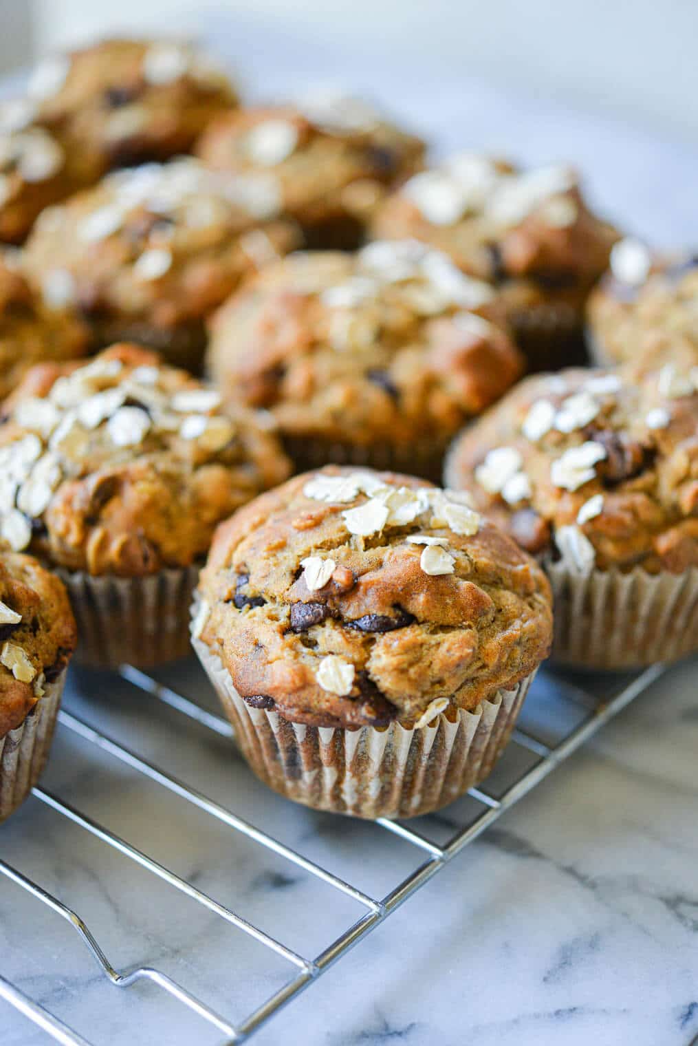 side angle view of chocolate chip banana oat muffins on a wire rack on a marble surface