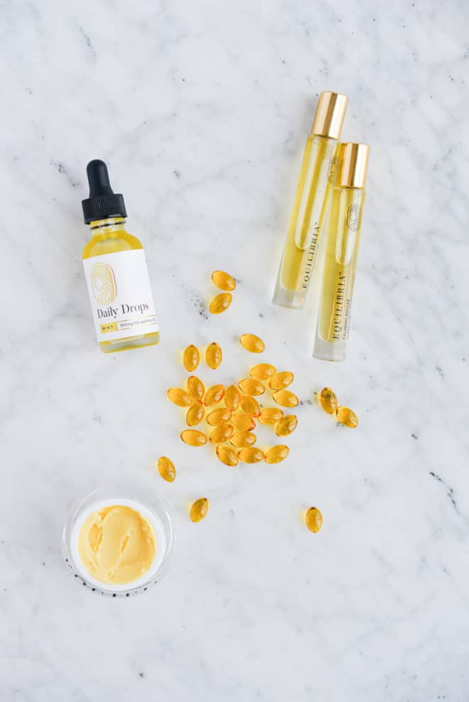 equilibria cbd drops, rollers, cream, and softgels on a marble surface