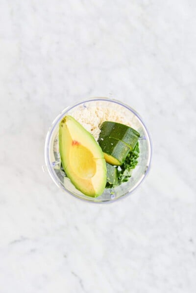 ingredients for green smoothies in an individual serving blender cup sitting on a marble surface