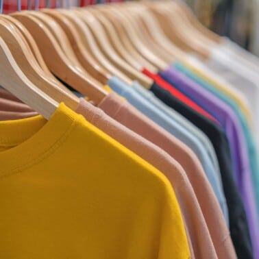 multiple colors of tshirts hanging on wooden hangers on a rack