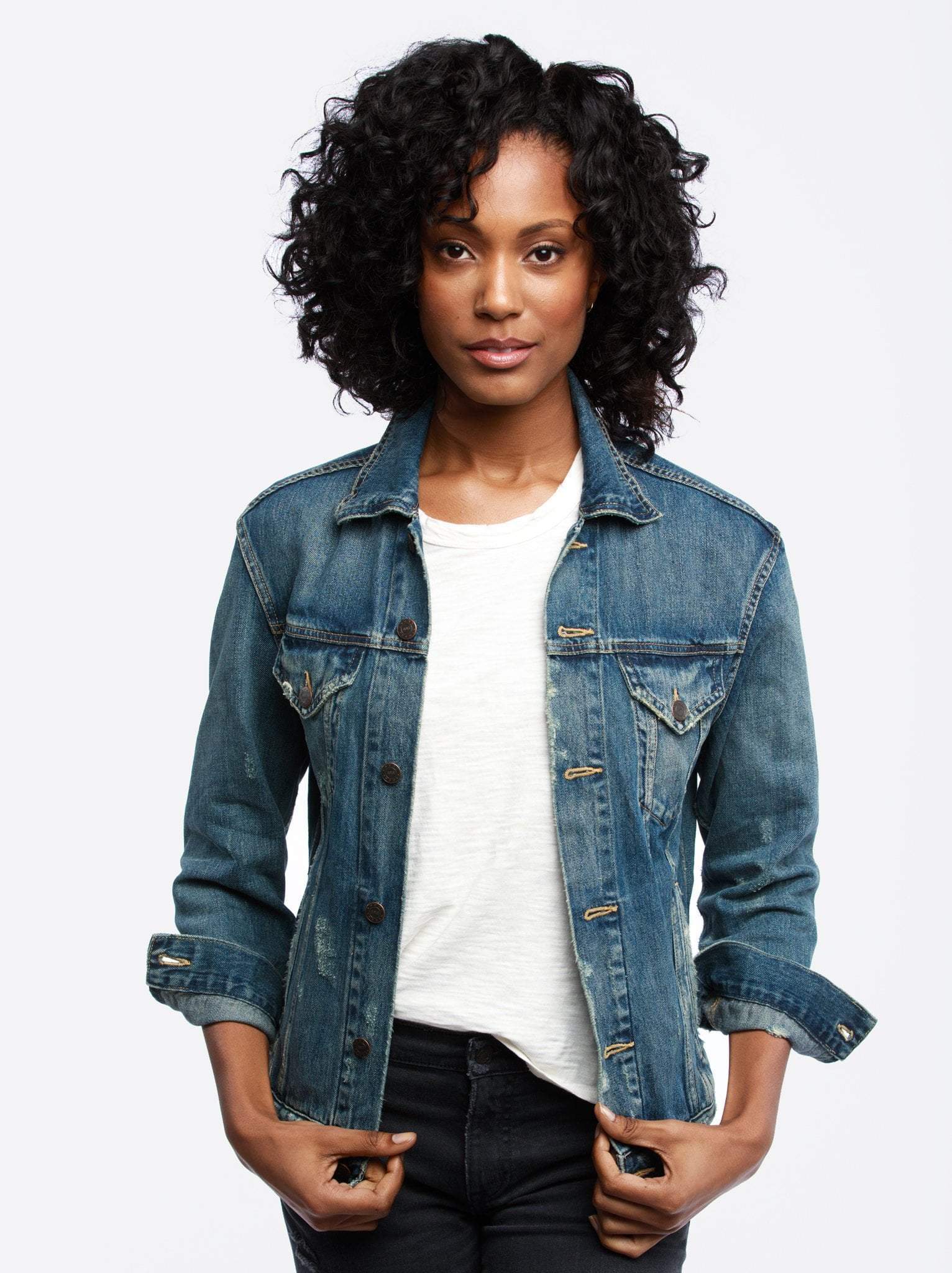 black woman with curly hair in a denim jacket, white tshirt, and black jeans