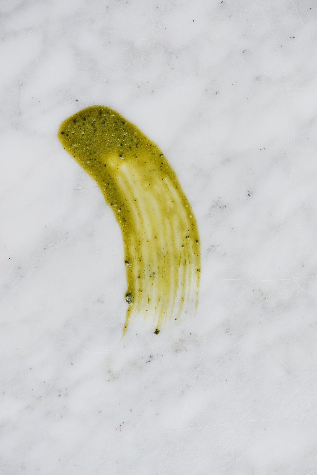 dark green smear of a matcha peel off mask on a marble surface