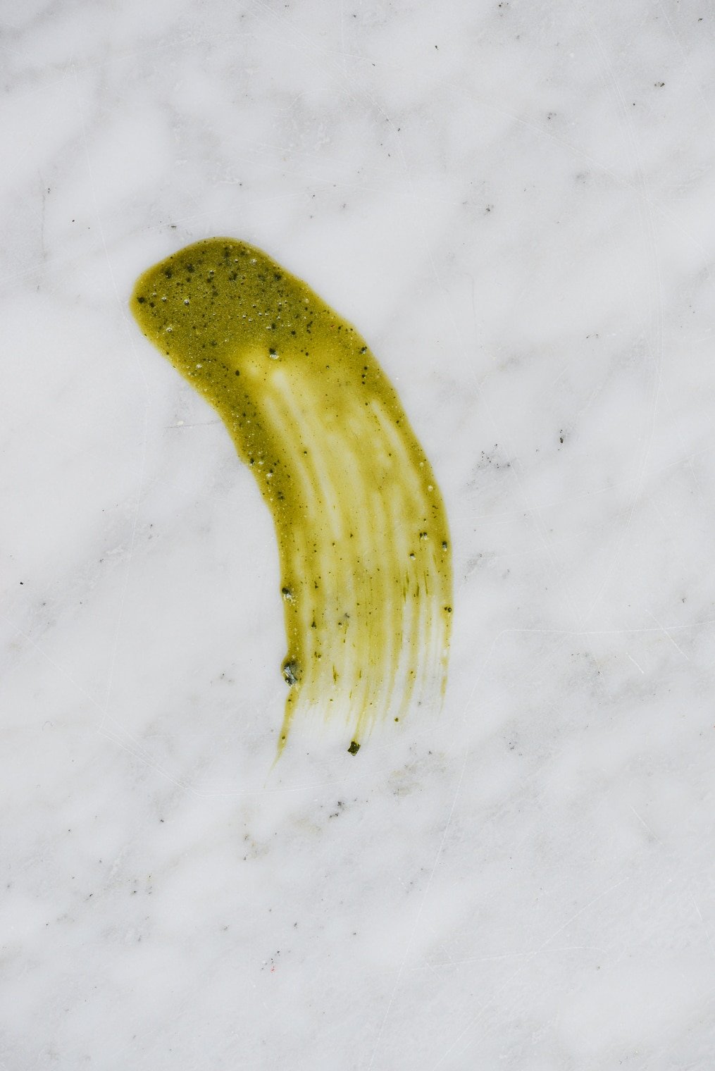 donkergroene uitstrijkjes van een matcha peel off masker op een marmeren ondergrond