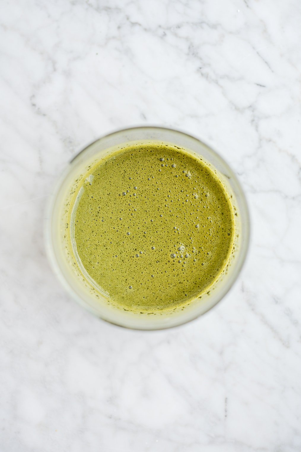 dark green peel-off face mask in a glass jar on a marble surface