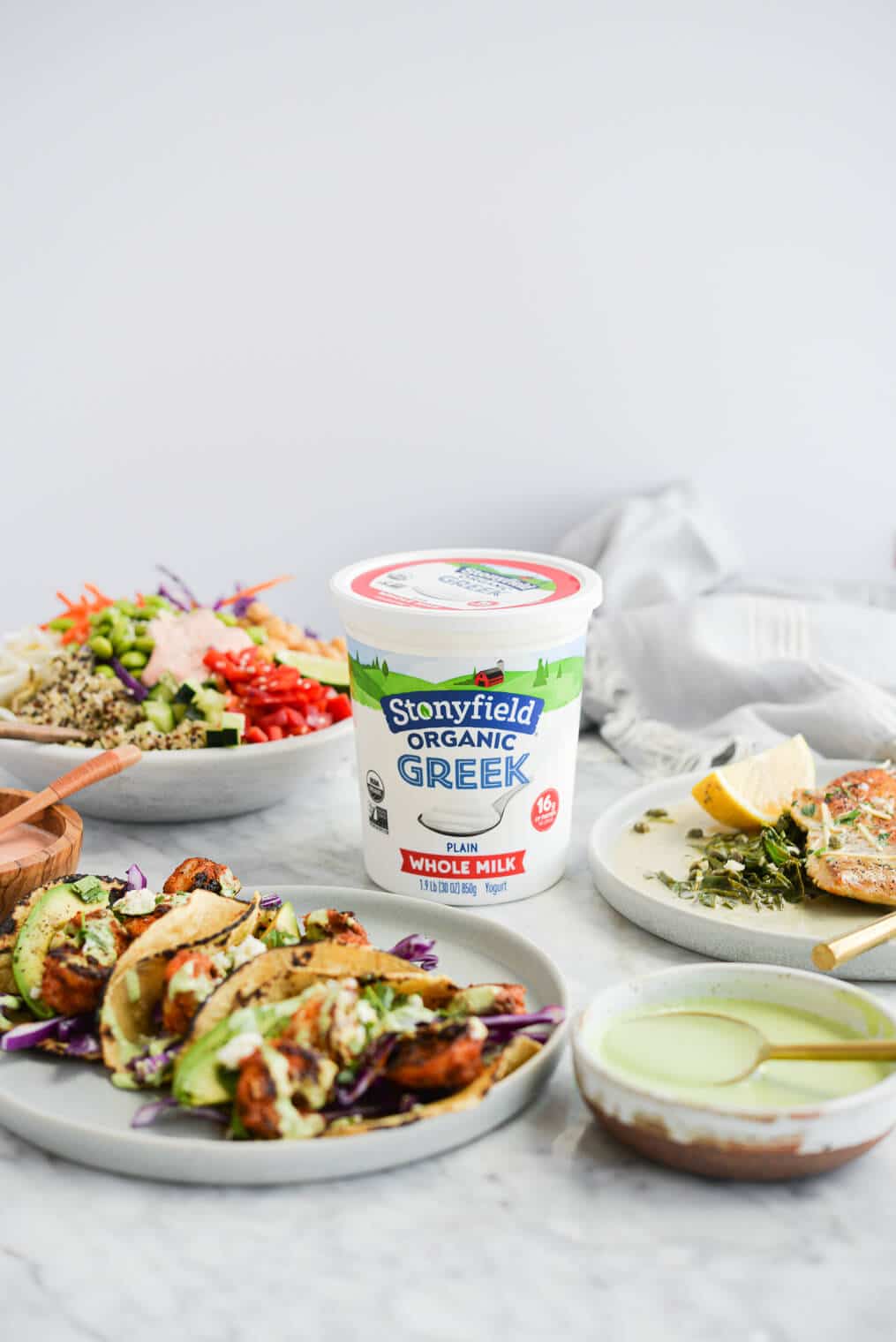 a thai red curry buddha bowl, three shrimp tacos, and a plate of creamy chicken piccata all surrounding a quart of Stonyfield's plain greek yogurt