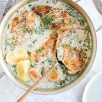 the top view of a skillet of creamy chicken piccata sprinkled with parmesan cheese on a marble surface