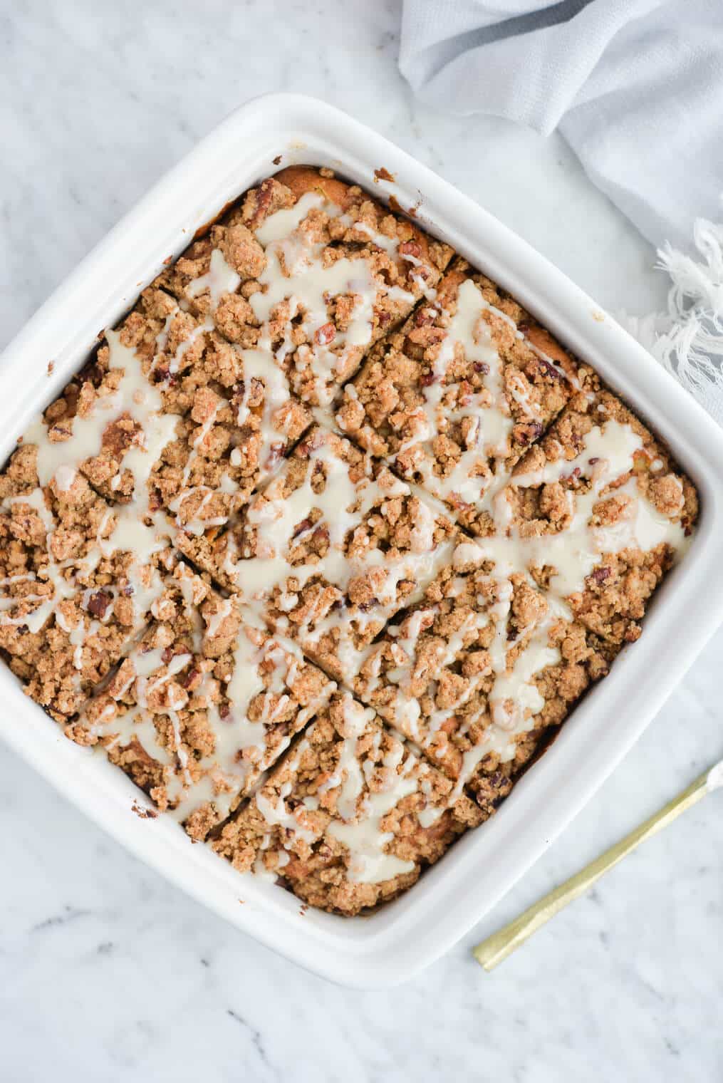 the top view of a dish of iced apple coffee cake sliced into individual pieces and sitting on a marble surface