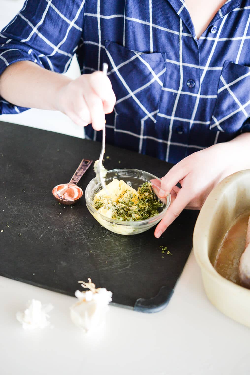 side view of herbs and butter being combined in a small glass bowl