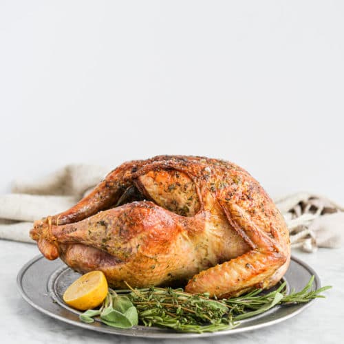 Young woman measuring temperature of whole roasted turkey with meat  thermometer Stock Photo